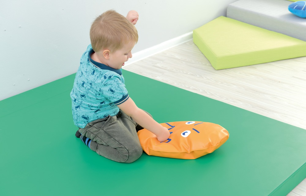 Dítě s emocionální pomůckou v terapeutické místnosti. Pomůcky pro rozvoj emoční inteligence a zvládání emocí.