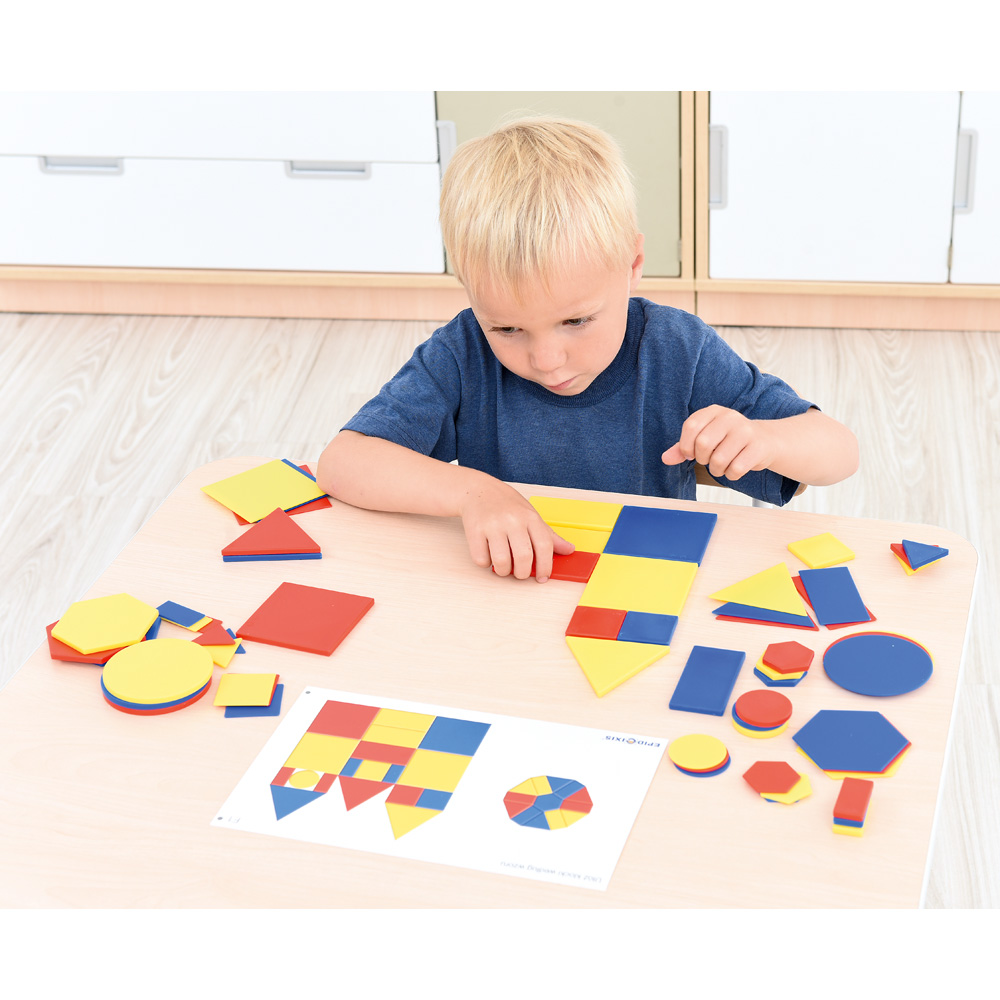 Chlapec skládá mozaiku z barevných geometrických tvarů.