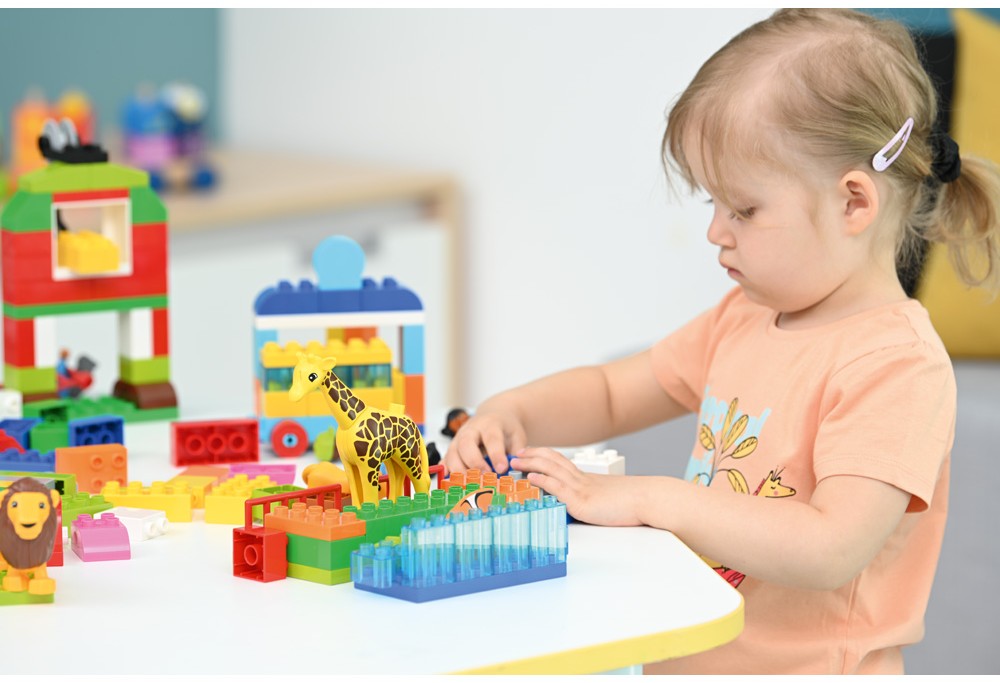 Skupina dětí používá LEGO SPIKE™ Essential k výstavbě a programování interaktivních projektů, s důrazem na STEM učení.