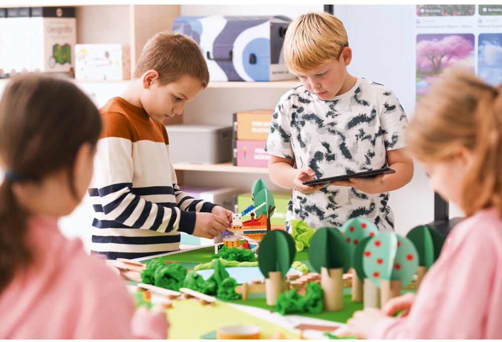 Děti staví modely z LEGO a využívají tablet jako nástroj pro tvorbu a podporu, zatímco se zabývají kreativními a vědeckými aktivitami.