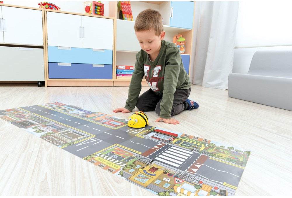 Chlapec ovládá robota Bee-Bot na hrací podložce se silnicemi a městem ve školce.