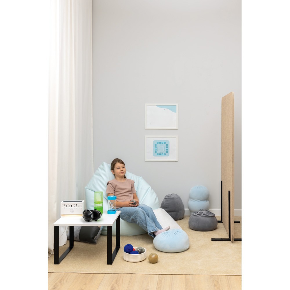 Chlapec leží na podlaze, drží relaxační polštáře kolem těla, různé polštáře a pytlíky kolem něj